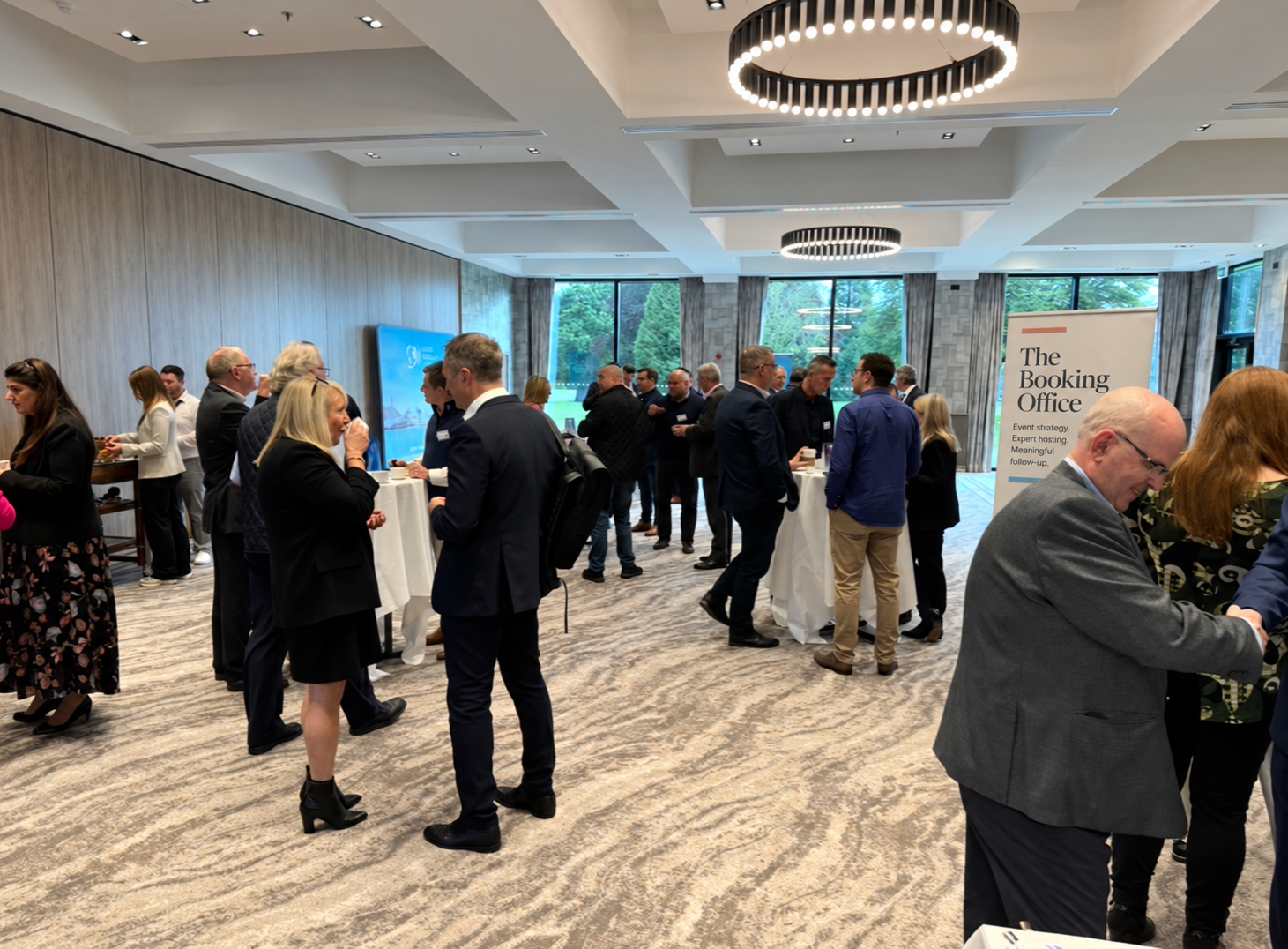Guests connecting in a bright reception room, with an edited Booking Office banner in the background